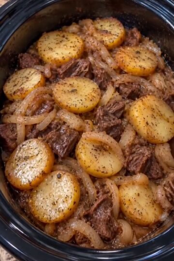 Slow cooker beef and potatoes with tender chuck, golden potato rounds, onions, and brown gravy