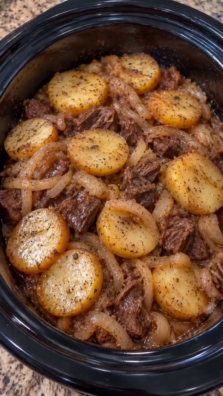 Slow cooker beef and potatoes with tender chuck, golden potato rounds, onions, and brown gravy